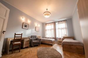 a room with two beds and a desk and a chair at Victus Apartamenty, Apartament Grande in Sopot