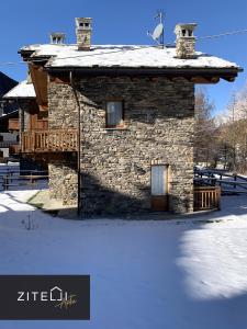 un bâtiment en pierre avec un toit recouvert de neige dans l'établissement Zitelli Aosta, à Cogne