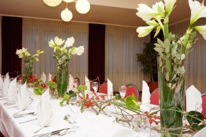 une table avec des fleurs blanches dans des vases dans l'établissement Airport Hotel Filder Post, à Stuttgart
