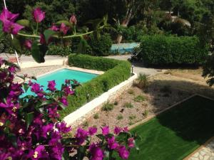 una piscina en un jardín con flores púrpuras en Résidence Le Golfe Bleu, en Rayol-Canadel-sur-Mer