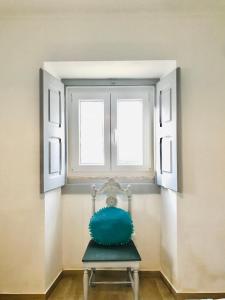 a chair in a room with two windows at Casas do Patheo in Óbidos