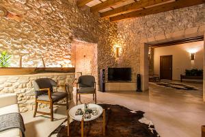 sala de estar con pared de piedra, sofá y sillas en Country House Sa Serra, en Lloret de Vistalegre