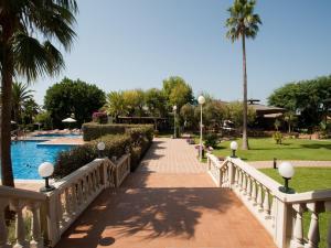 a bridge leading to a resort with a pool and palm trees at Pato Amarillo in Punta Umbría