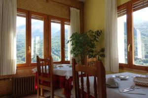ein Esszimmer mit Tisch, Stühlen und Fenstern in der Unterkunft Hotel Vicente in Panticosa
