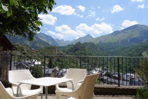 a table and chairs on a balcony with a view of mountains at Hotel Vicente in Panticosa