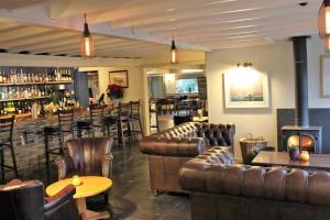 a bar with leather couches and tables and a fireplace at The Pityme Inn in Wadebridge