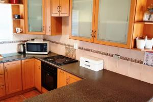 a kitchen with wooden cabinets and a stove top oven at Fairway 2 Holiday Home in Langebaan