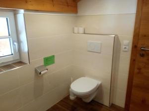 a white bathroom with a toilet and a window at Gsenghof in Filzmoos