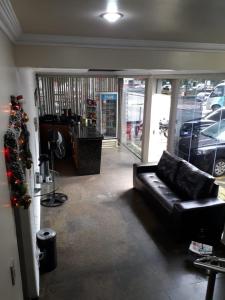 a living room with a black couch in front of a store at HOTEL D' LUCCA in Ubá