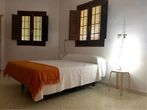 Un dormitorio con una cama y dos ventanas. en CENTRO DE OCIO ALÚA Casa Rural Iznájar Lago de Andalucía, en Iznájar