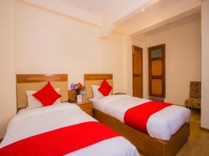 due letti in una stanza con lenzuola rosse e bianche di Durbar Guest House a Patan