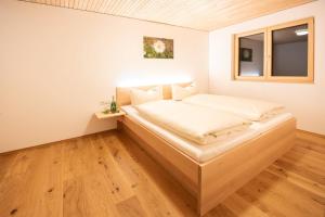 Bett in einem kleinen Zimmer mit Fenster in der Unterkunft Wiesenhof Rusch in Alberschwende