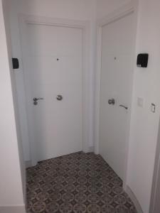 a hallway with two white doors and a tile floor at Bajo Gerona in Seville +17 photos