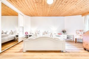 - une chambre dotée d'un mobilier blanc et d'un plafond en bois dans l'établissement Chalet Zentral Bach by A-Appartments, à Brand
