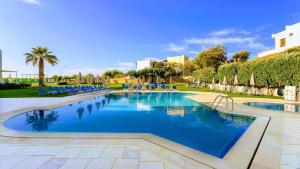 a large swimming pool with blue chairs and trees at Pela Sofia in Stalís