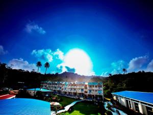 a view of a resort with palm trees and the sun at Hummingbird Resort in Mount Ābu