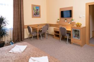 a hotel room with a desk and a table and a tv at Aquasol Resort in Mosonmagyaróvár