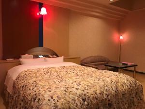 a bedroom with a bed and a table with a chair at HOTEL Fairy tale 養父店 in Yōka