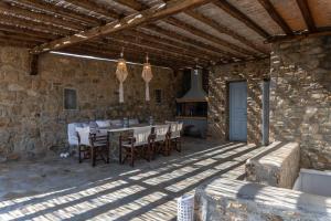 patio ze stołem i krzesłami w kamiennym budynku w obiekcie Summer Mood Villas (6 bedroom villa) w mieście Mykonos