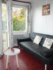 sala de estar con sofá negro y mesa en Les Chalets des Mousquetaires en Mirepoix