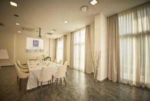 a dining room with a table and white chairs at iH Hotels Milano Lorenteggio in Milan