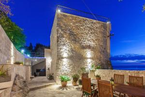 a patio with a table and chairs and a stone wall at 19th Century stone art house in NATURE PARK in Makarska