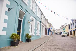 een geplaveide straat in een stad met blauwe gebouwen bij The Victoria in Alderney