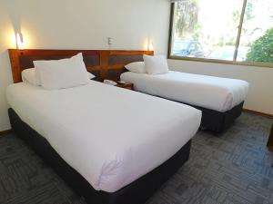 two beds in a hotel room with white sheets at Hotel Mar Andino in Rancagua
