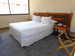 a bedroom with a large white bed and a telephone at Hotel Mar Andino in Rancagua