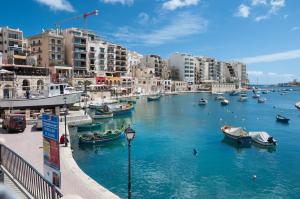 a river with boats in a city with buildings at Apartment with Pool in Sliema