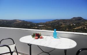 uma mesa branca com uma garrafa azul e flores sobre ela em Galini Apartments em Plakiás