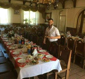 a man holding a plate of food at a long table at Медовий in Vorokhta