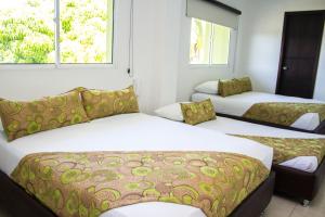 a room with three beds and two windows at Terra Toscana Hotel in Mangue