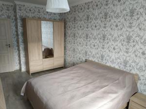 Schlafzimmer mit einem Bett, einem Spiegel und Tapeten in der Unterkunft Comfort Apartment on Bogdanivska street 7b in Kiew