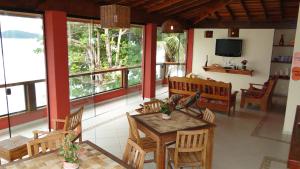 a living room with a table and chairs and windows at Pousada Casa na Praia in Ubatuba