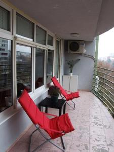 2 sillas rojas y una mesa en el balcón en Arena Apartman en Belgrado