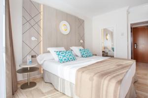 a bedroom with a large white bed with blue pillows at Grupotel Los Príncipes & Spa in Playa de Muro