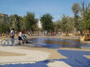 セビリアにあるApartamento Faustino Alvarezの噴水の横を自転車で歩く男女