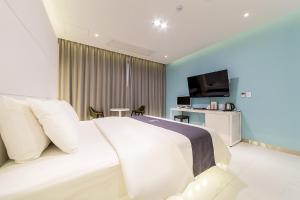 a bedroom with a white bed and a television at Rosabell Hotel in Ansan
