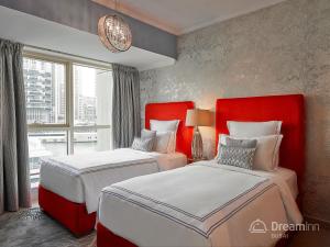 1 dormitorio con 2 camas con cabeceras rojas y ventana en Dream Inn Apartments - Marina Quays, en Dubái
