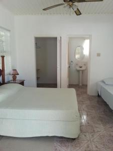 a white bedroom with a bed and a bathroom at Polish Princess Guest House in Port Antonio