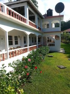 a large white house with flowers in the yard at Polish Princess Guest House in Port Antonio