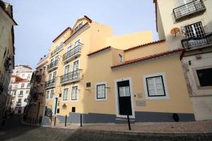 a yellow building with a black door on a street at Alfama Right Point in Lisbon