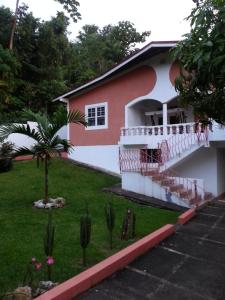 a house with a balcony and a yard at Polish Princess Guest House in Port Antonio