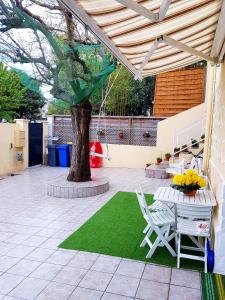 une terrasse avec un arbre, une table et des chaises dans l'établissement MAISON APPARTEMENT TOUT CONFORT À 10mn des plages, à Montpellier