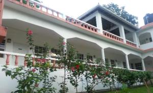 a white building with a balcony with red roses at Polish Princess Guest House in Port Antonio
