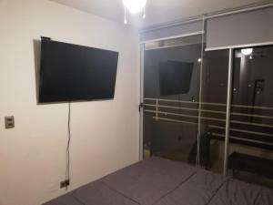 1 dormitorio con 1 cama y TV en la pared en Costa Algarrobo Norte, en Algarrobo