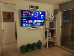sala de estar con TV de pantalla plana en la pared en Costa Algarrobo Norte, en Algarrobo