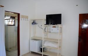 a room with a white shelf with a tv on it at Pousada Farol do Itaguá in Ubatuba