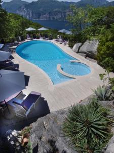 una gran piscina con sillas y vistas al agua en Hotel Querceto Wellness & Spa - Garda Lake Collection, en Malcesine